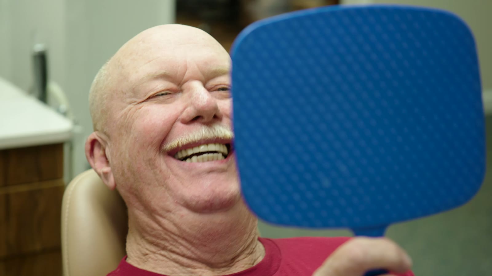 A Tim Rauch DDS patient seeing their new smile in the mirror